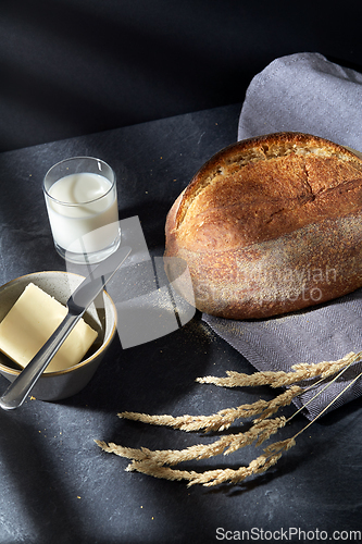 Image of close up of bread, butter, knife and glass of milk