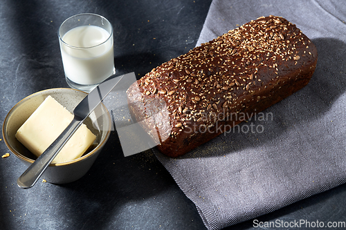 Image of close up of bread, butter, knife and glass of milk