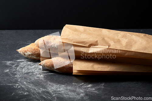 Image of close up of baguette bread in paper bags on table