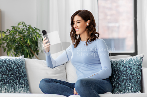 Image of woman with earphones and smartphone at home