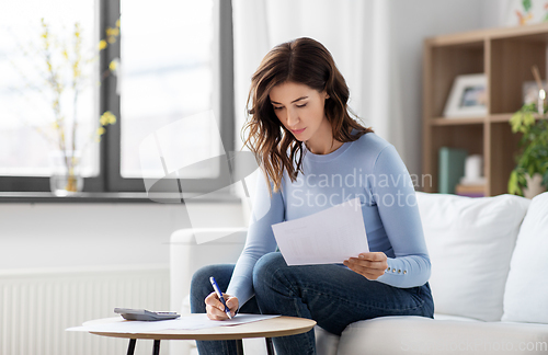 Image of woman with papers and calculator at home