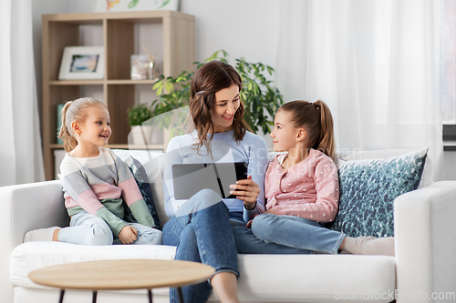 Image of happy mother and daughters with tablet pc at home