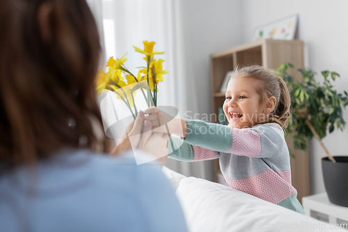 Image of happy daughter giving daffodil flowers to mother