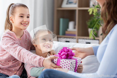 Image of daughters giving present to happy mother