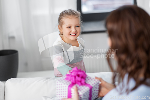 Image of happy daughter giving present to mother at home