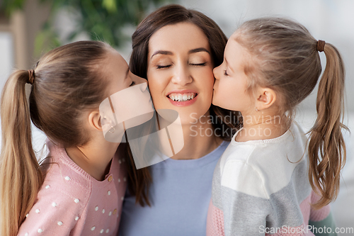 Image of happy mother and two daughters kissing her at home
