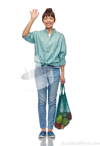 Image of happy asian woman with food in reusable string bag