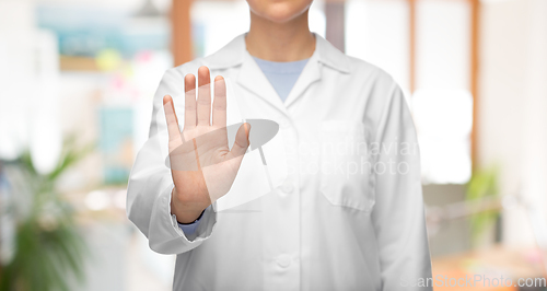 Image of female doctor in white coat showing stop gesture