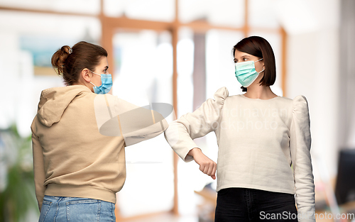 Image of women in masks making elbow bump greeting gesture