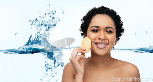 Image of young woman cleaning face with exfoliating sponge