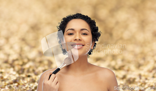 Image of woman with make up brush applying shimmer to skin