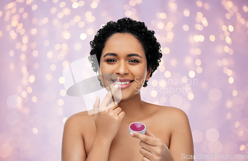 Image of african american woman applying lip gloss