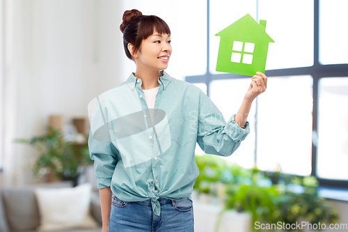 Image of smiling asian woman holding green house