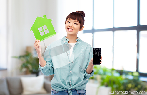 Image of smiling asian woman holding green house