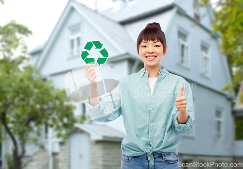 Image of smiling asian woman holding green recycling sign