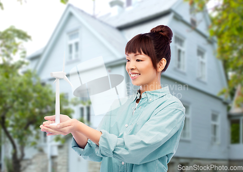 Image of smiling young asian woman with toy wind turbine