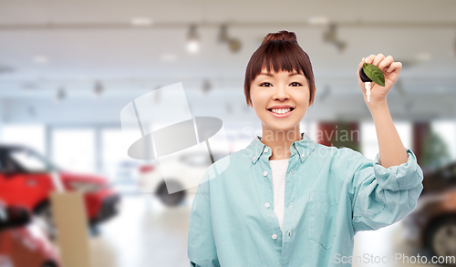 Image of happy asian woman holding car key with green leaf