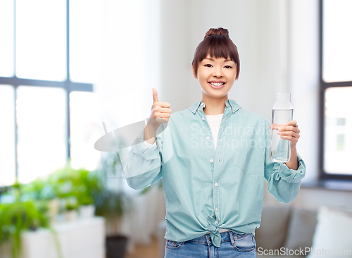 Image of happy asian woman holding glass bottle with water