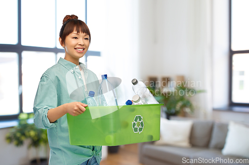 Image of smiling young asian woman sorting plastic waste