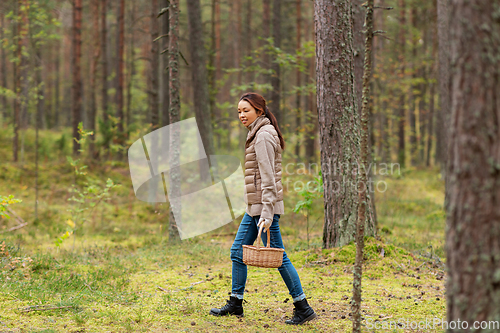 Image of young woman picking mushrooms in autumn forest