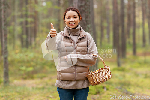 Image of woman with mushrooms showing thumbs up in forest