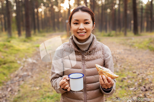 Image of woman with mushrooms drinks tea and eats in forest