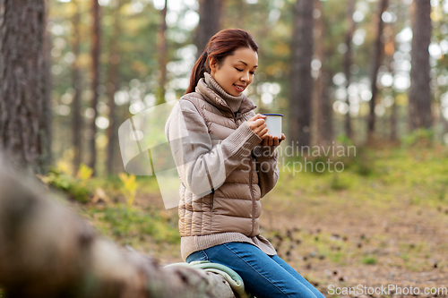 Image of asian woman with mug drinking tea in forest