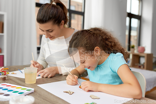 Image of happy mother with little daughter drawing at home