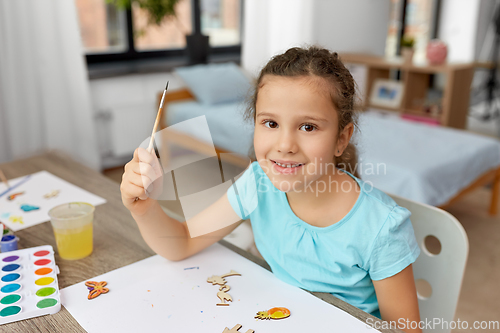 Image of little girl painting wooden items at home