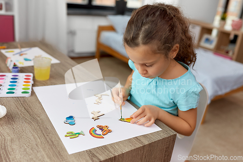 Image of little girl painting wooden items at home