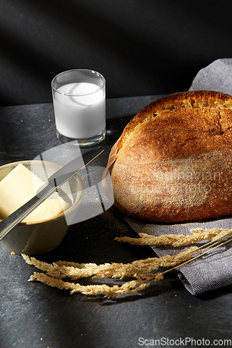 Image of close up of bread, butter, knife and glass of milk