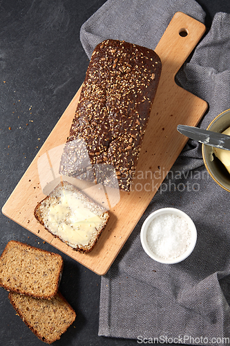 Image of close up of bread, butter, knife and salt on towel