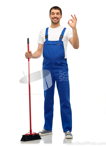 Image of male cleaner in overall cleaning floor with broom