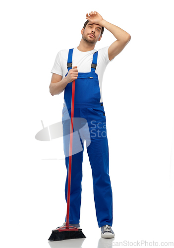Image of tired male cleaner cleaning floor with broom