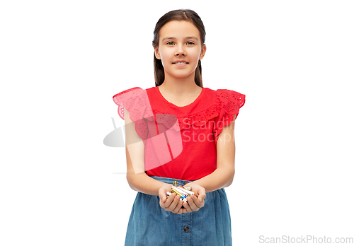 Image of smiling girl holding pile of alkaline batteries