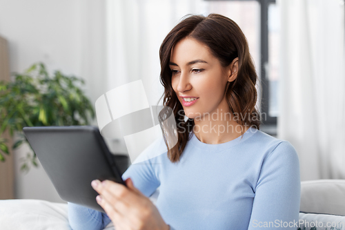 Image of happy smiling young woman with tablet pc at home
