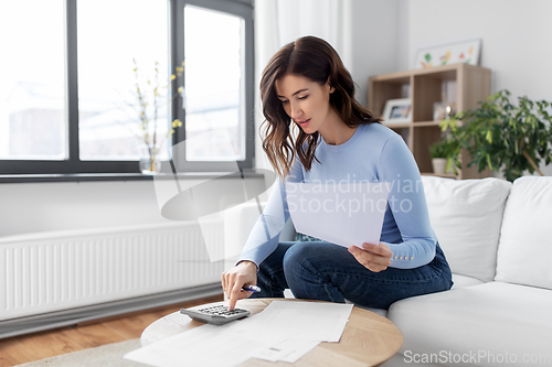 Image of woman with papers and calculator at home