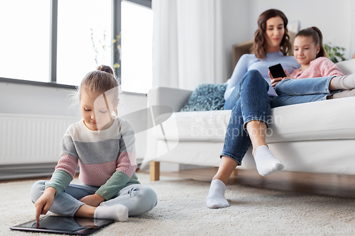 Image of happy girl with tablet pc and family at home