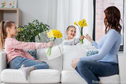 Image of daughters giving daffodil flowers to happy mother