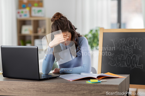 Image of teacher with laptop and notebook working from home