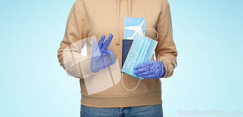 Image of woman with mask, passport and ticket shows ok sign