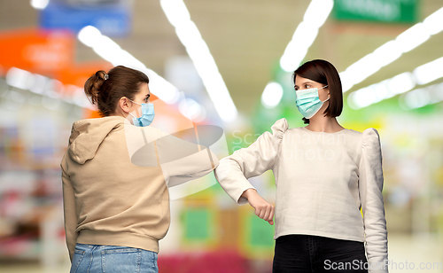 Image of women in masks making elbow bump greeting gesture