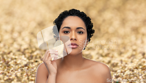 Image of young woman cleaning face with exfoliating sponge