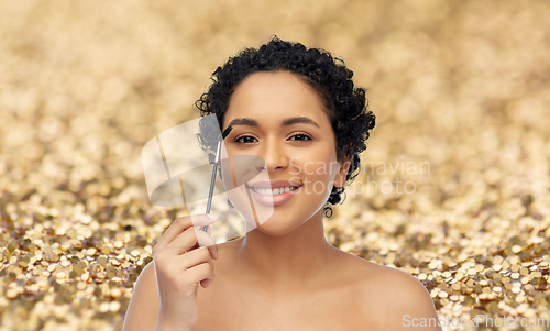 Image of smiling african american woman with mascara brush