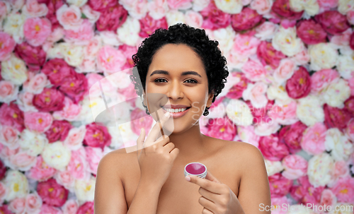 Image of african american woman applying lip gloss