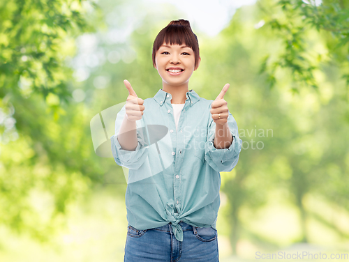 Image of happy asian woman showing thumbs up over white
