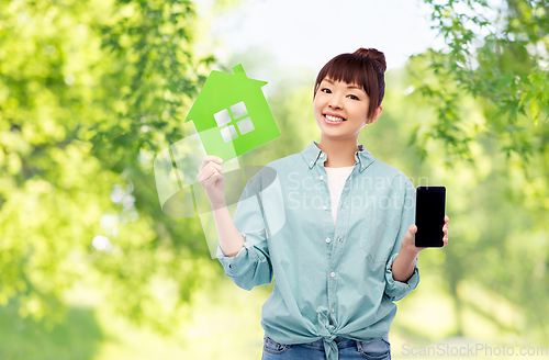 Image of smiling asian woman holding green house