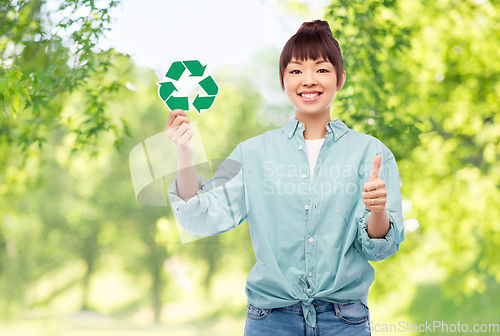 Image of smiling asian woman holding green recycling sign