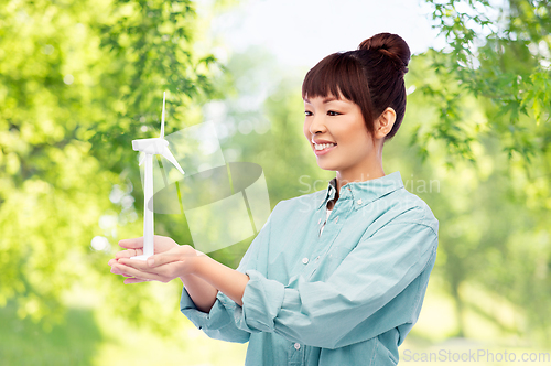 Image of smiling young asian woman with toy wind turbine