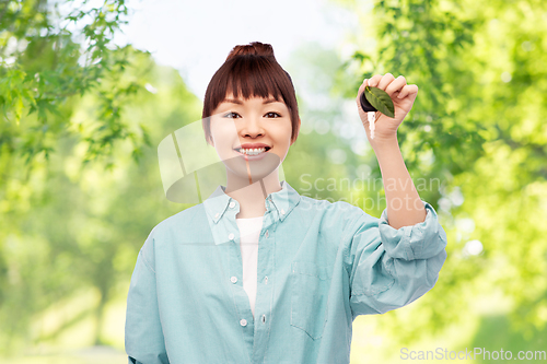 Image of happy asian woman holding car key with green leaf